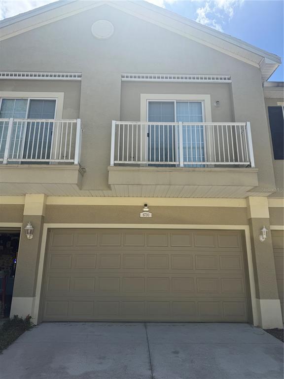 The exterior of a two-story townhouse features a garage, two balconies, and beige stucco siding — 6730 EAGLE FEATHER DRIVE, RIVERVIEW, FL