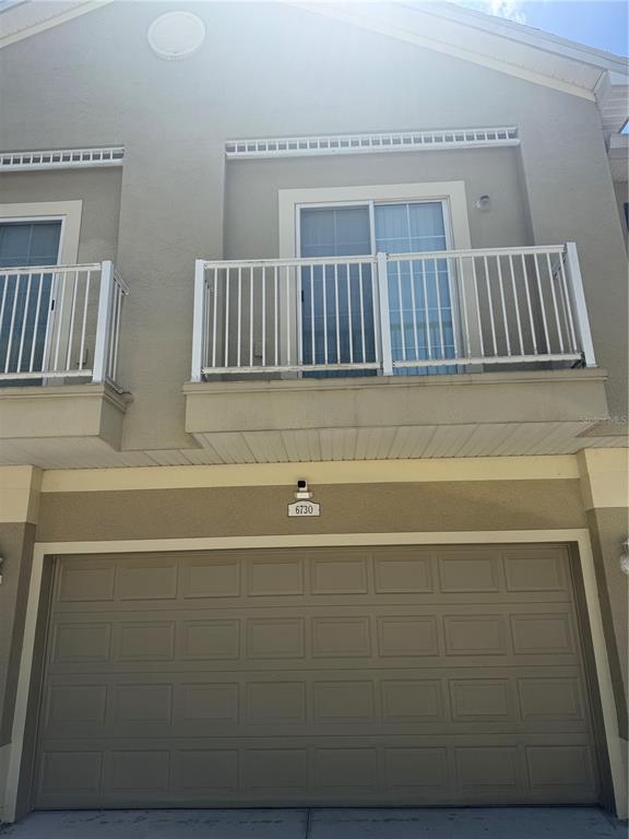 The exterior of a two-story building features a garage, two balconies, and beige stucco walls — 6730 EAGLE FEATHER DRIVE, RIVERVIEW, FL