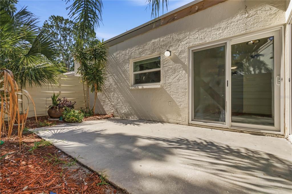 A concrete patio sits outside a house with a sliding glass door and a window — 2628 CEDAR VIEW COURT, CLEARWATER, FL