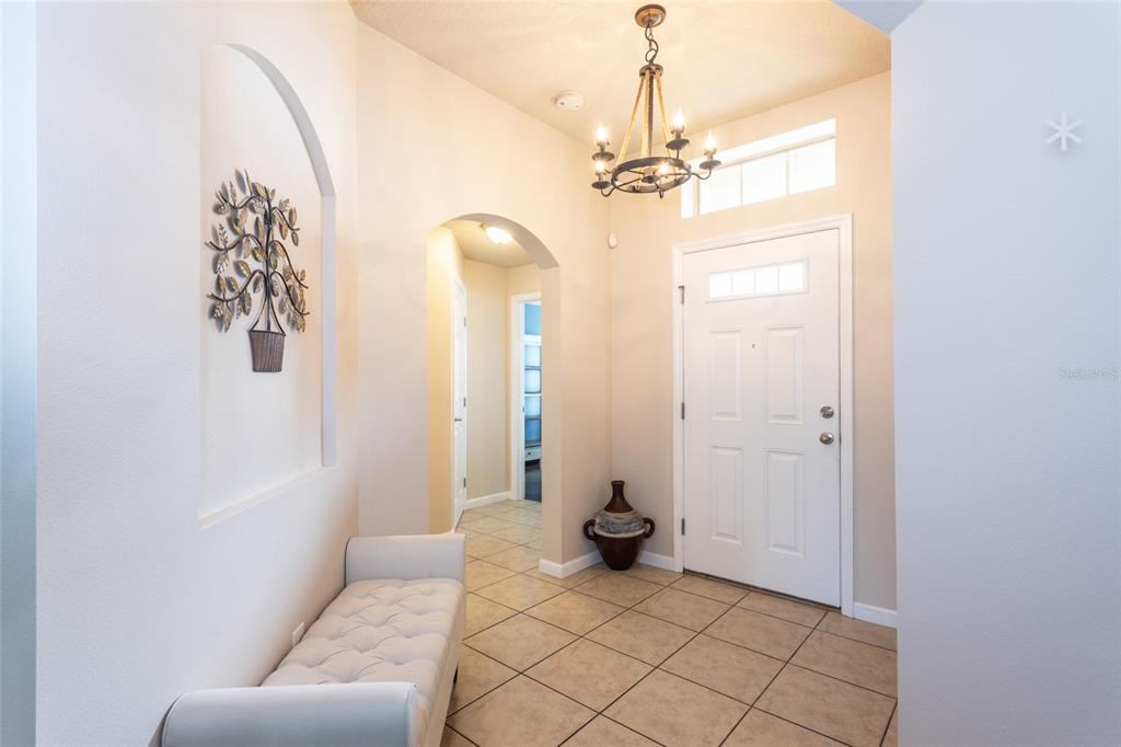 A tiled entryway features an arched wall niche, a tufted bench, and a rustic chandelier — 118 GOLFVIEW COURT, BUNNELL, FL