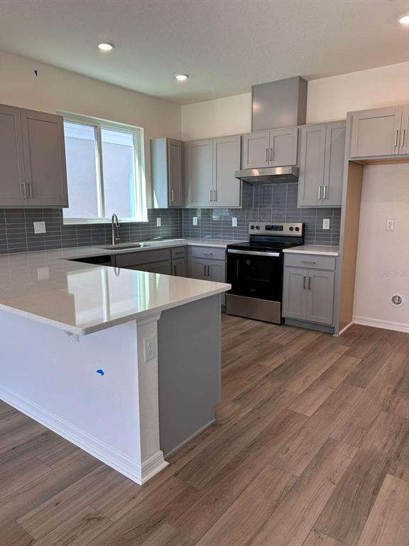 A kitchen with gray cabinets, white countertops, a gray tile backsplash, and wood-look flooring — 16553 BROOK ISLE WAY, CLERMONT, FL