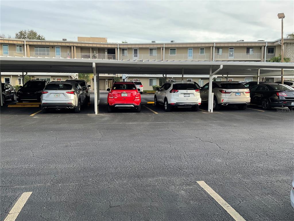 A covered parking area features several cars parked in front of a multi-story apartment building — 2244 WINKLER AVENUE UNIT 301, FORT MYERS, FL