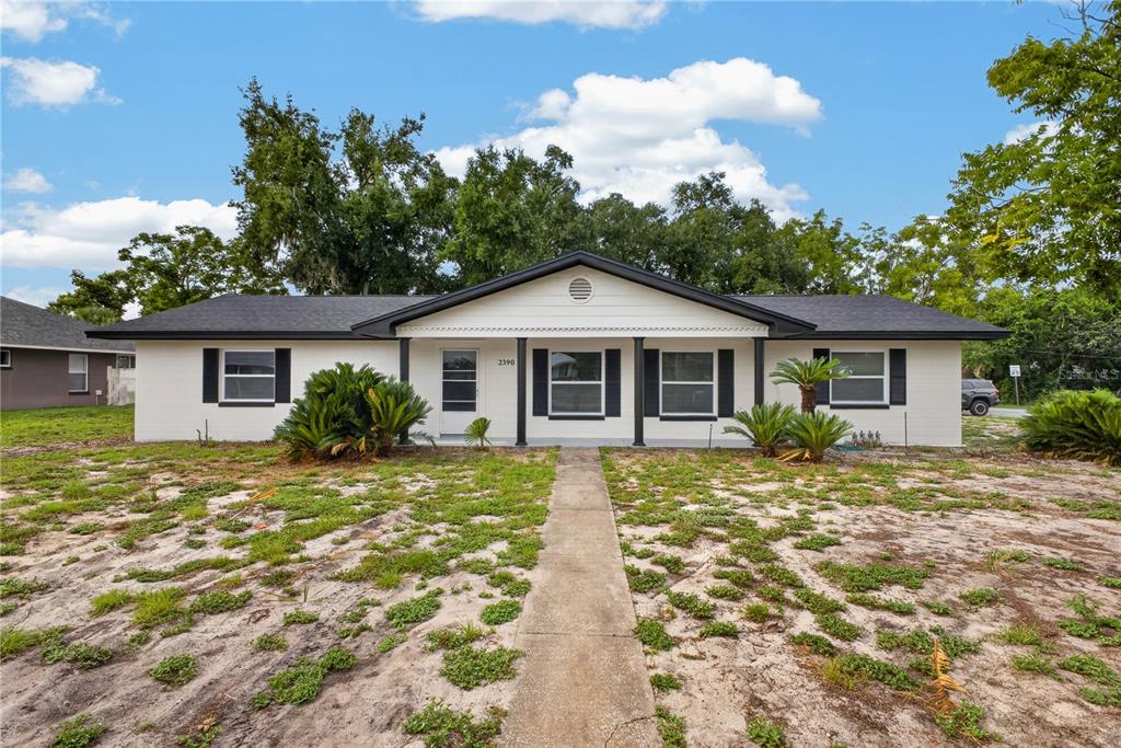 An aerial view shows a single-story house with a dark roof and a front lawn — 2390 NORTHLAND ROAD, MOUNT DORA, FL