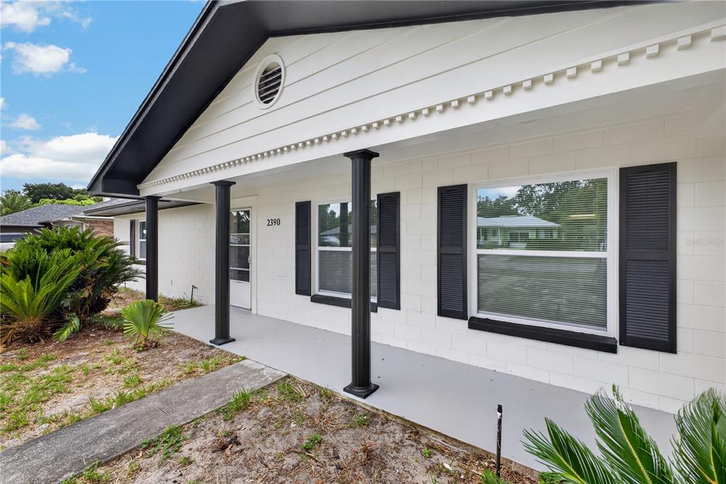 A single-story house with white brick walls, black shutters, and a sandy front yard — 2390 NORTHLAND ROAD, MOUNT DORA, FL