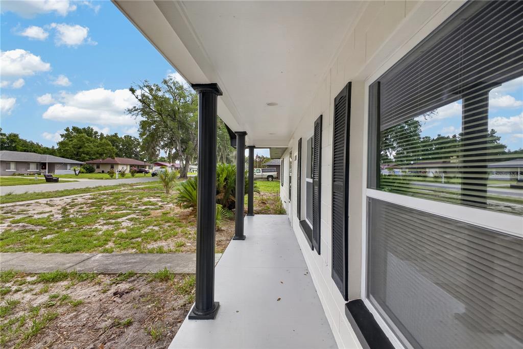 A white concrete block house features a covered front porch with black columns and shutters — 2390 NORTHLAND ROAD, MOUNT DORA, FL