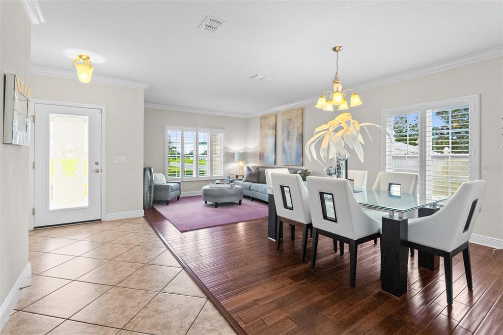 A dining area with a glass table and white chairs transitions into a living room — 301 SPARROW HAWK DRIVE, GROVELAND, FL
