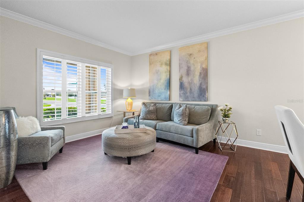 A living room features a grey sofa, matching armchair, round ottoman, and a purple area rug — 301 SPARROW HAWK DRIVE, GROVELAND, FL