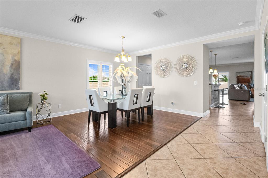 A dining area with a glass table and white chairs sits on dark wood flooring — 301 SPARROW HAWK DRIVE, GROVELAND, FL