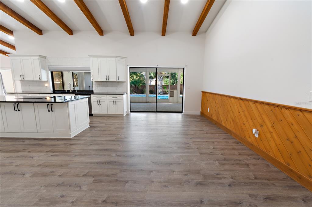 A kitchen and dining area feature white cabinets, wood ceiling beams, and diagonal wood wainscoting — 280 SANTA ROSA DRIVE, WINTER HAVEN, FL