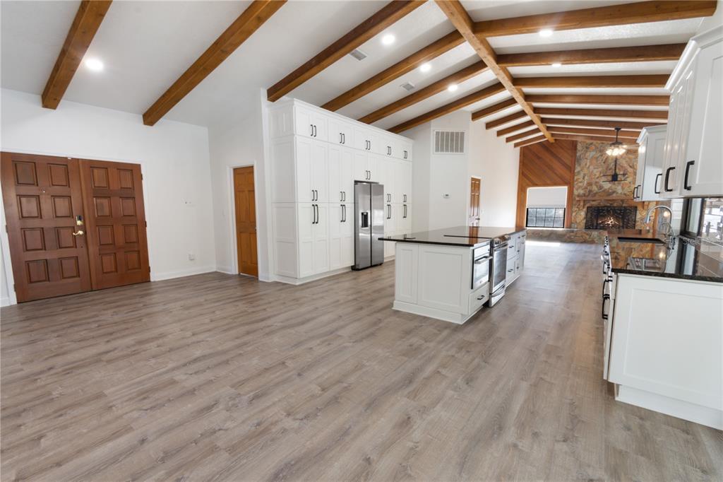 A spacious kitchen with white cabinets, a large island, and exposed wood ceiling beams — 280 SANTA ROSA DRIVE, WINTER HAVEN, FL