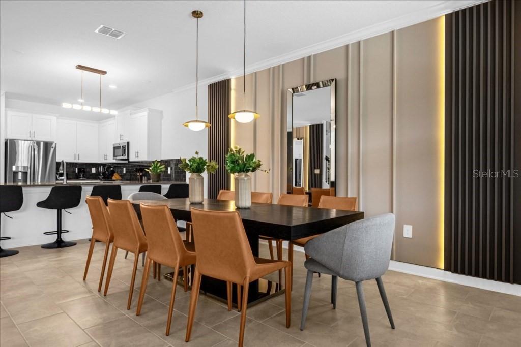 A dining area features a dark table, tan chairs, and a wall with vertical slats — 2992 PENELOPE LOOP, KISSIMMEE, FL