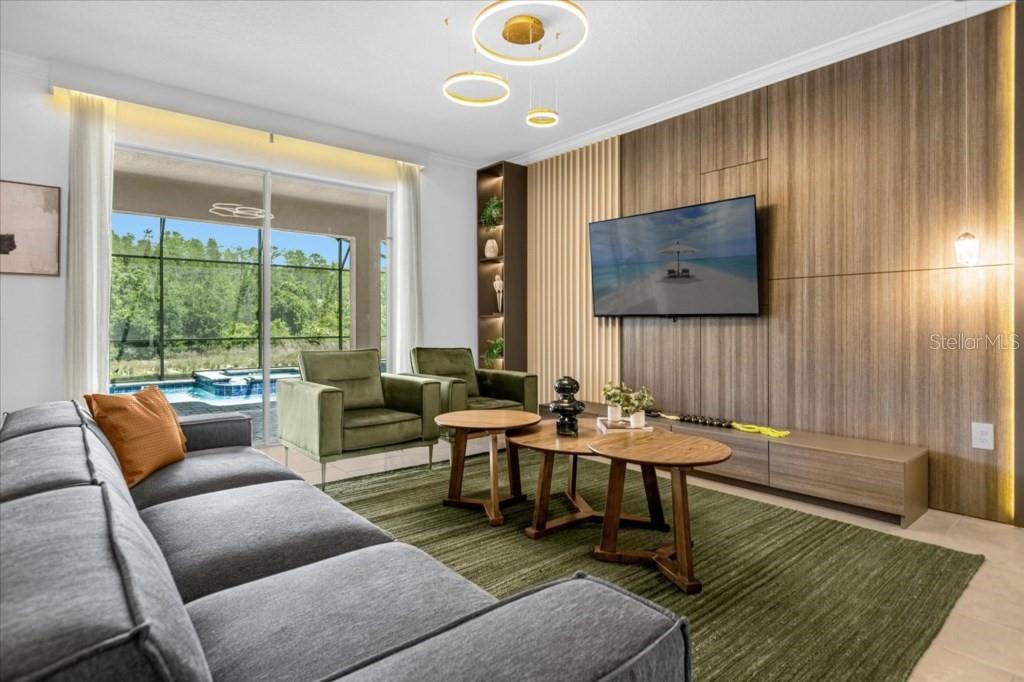 A living room features a gray sofa, green armchairs, wood paneling, and a pool view — 2992 PENELOPE LOOP, KISSIMMEE, FL