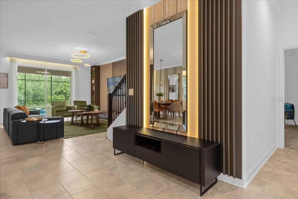 A modern entryway features a black console table, a tall mirror, and vertical wood slats — 2992 PENELOPE LOOP, KISSIMMEE, FL