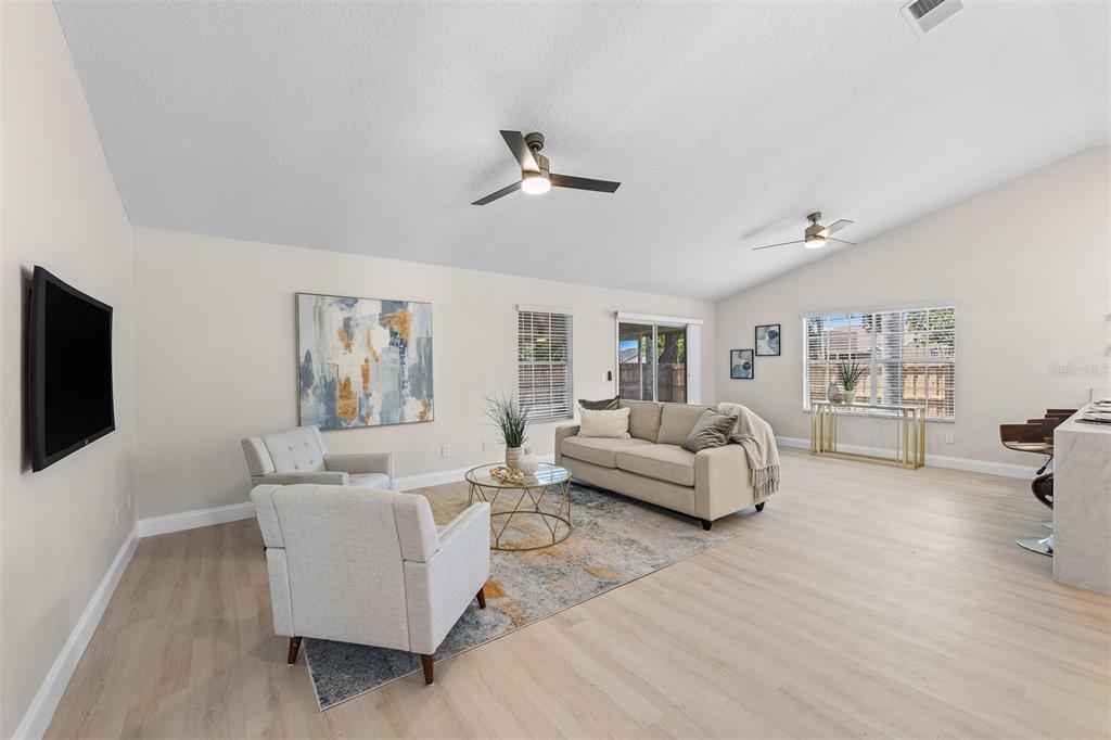 A living room features light wood flooring, a beige sofa, two armchairs, and vaulted ceilings — 6572 ABERCROMBIE COURT, ORLANDO, FL