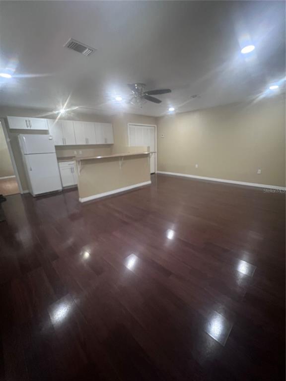 A kitchen with white cabinets and a breakfast bar opens into a large living area — 6426 DELTA LEAH DRIVE, ORLANDO, FL
