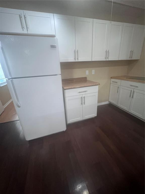 A kitchen features white shaker-style cabinets, a white refrigerator, and dark wood-look flooring — 6426 DELTA LEAH DRIVE, ORLANDO, FL