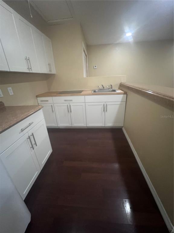 A kitchen features white cabinets, a light countertop with a sink, and dark wood flooring — 6426 DELTA LEAH DRIVE, ORLANDO, FL