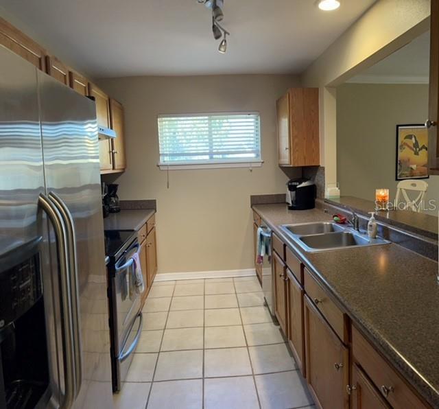A kitchen features stainless steel appliances, wood cabinets, a window, and dark laminate countertops — 1818 PARAKEET WAY UNIT 1001, SARASOTA, FL