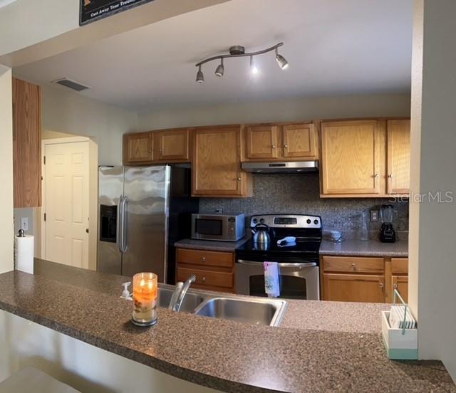 A kitchen features wood cabinets, stainless steel appliances, and a granite-topped breakfast bar — 1818 PARAKEET WAY UNIT 1001, SARASOTA, FL