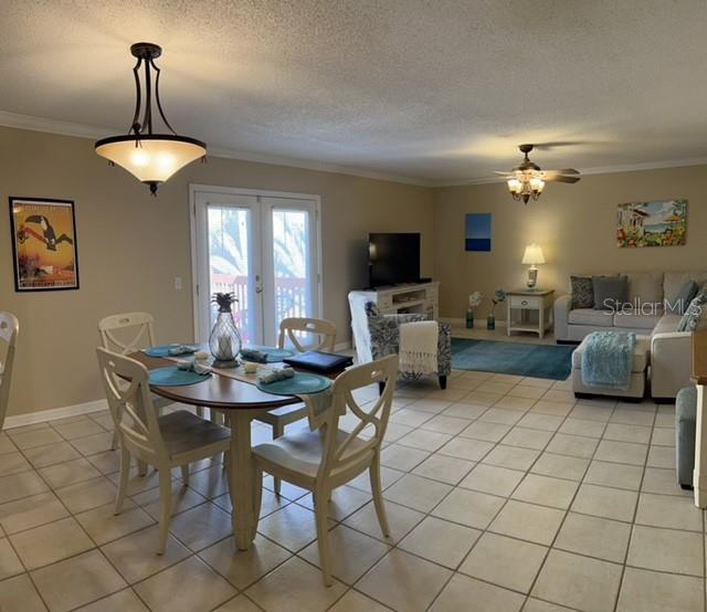 An open-concept living and dining area features tile flooring, a ceiling fan, and French doors — 1818 PARAKEET WAY UNIT 1001, SARASOTA, FL