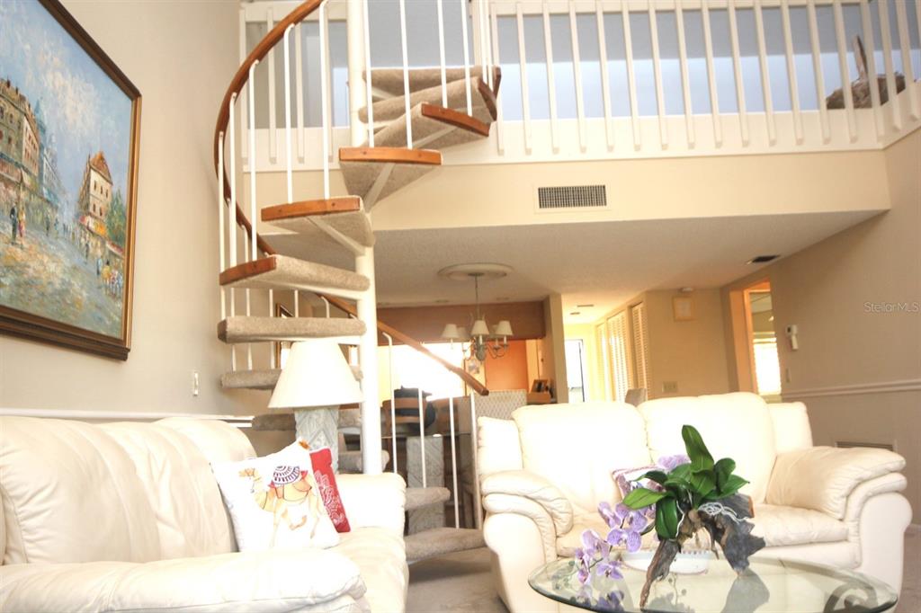 A living room features a spiral staircase, white leather sofas, and a glass coffee table — 1255 DOCKSIDE PLACE UNIT 211, SARASOTA, FL