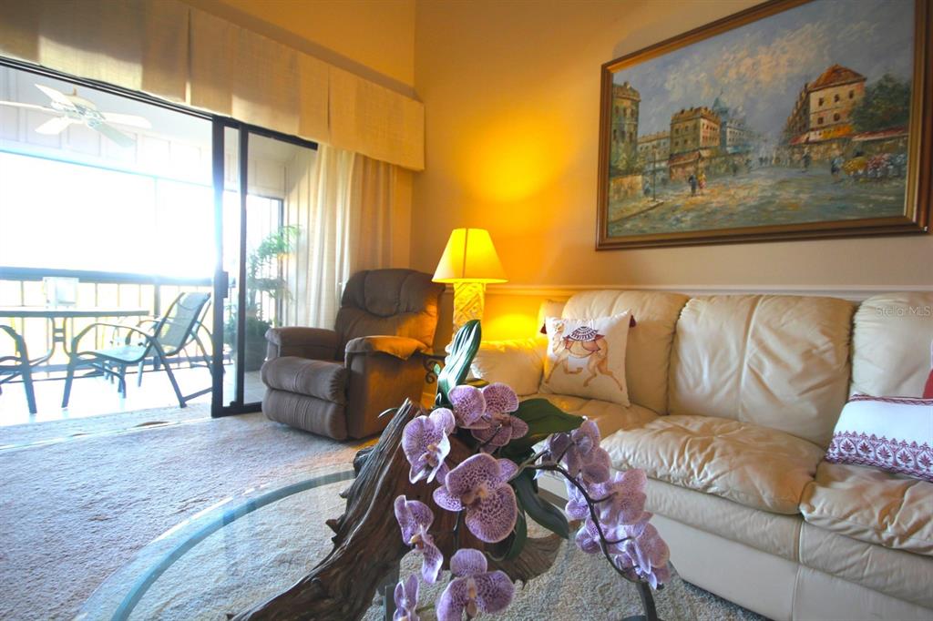 A living room features a beige leather sofa, a brown recliner, and a glass coffee table — 1255 DOCKSIDE PLACE UNIT 211, SARASOTA, FL