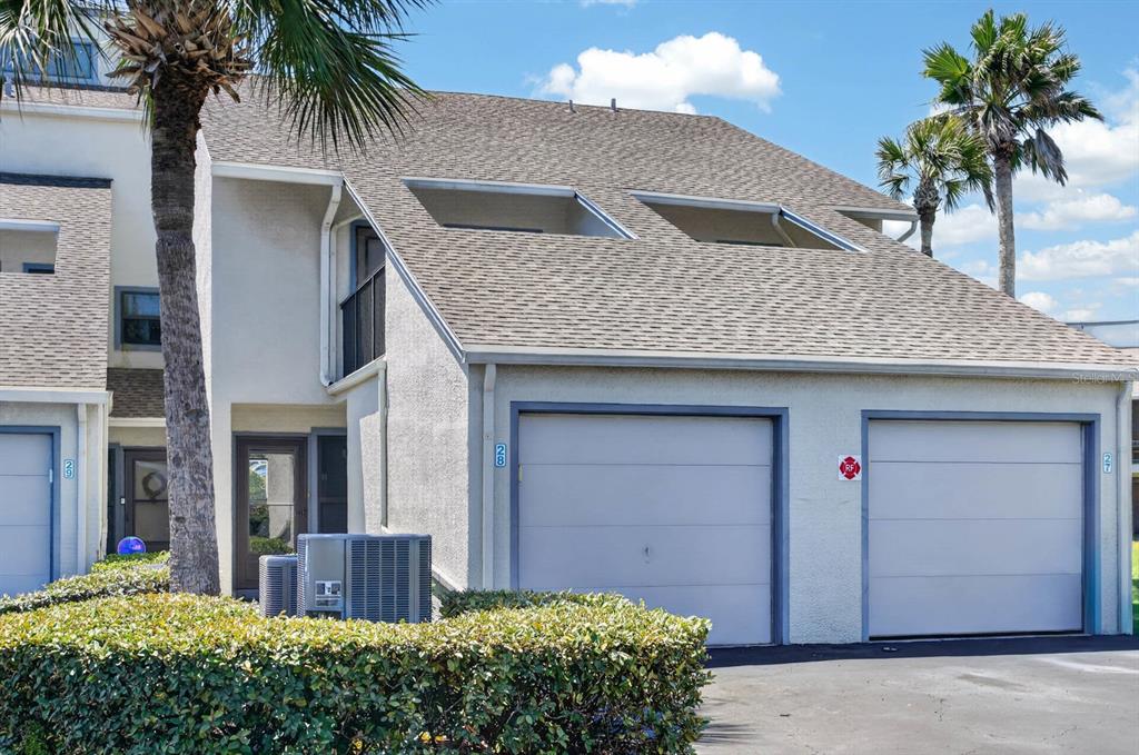An exterior view of a multi-story townhouse with two garage doors and a palm tree — 890 A1A BEACH BLVD #28 UNIT 28, ST AUGUSTINE, FL