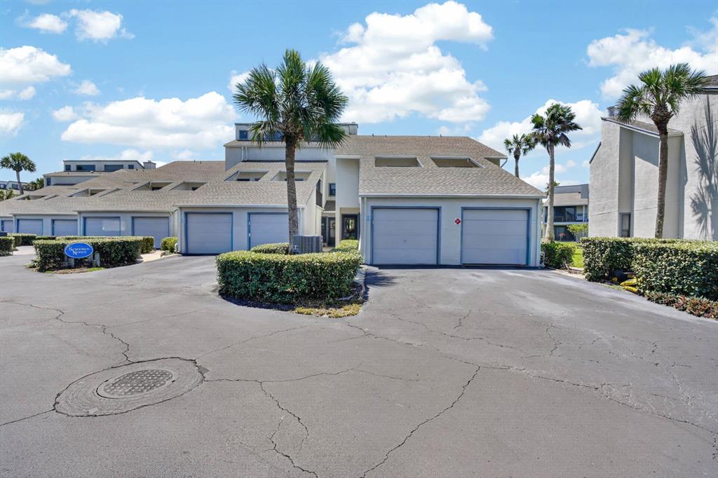 A multi-unit residential building features several garage doors, palm trees, and a paved driveway — 890 A1A BEACH BLVD #28 UNIT 28, ST AUGUSTINE, FL