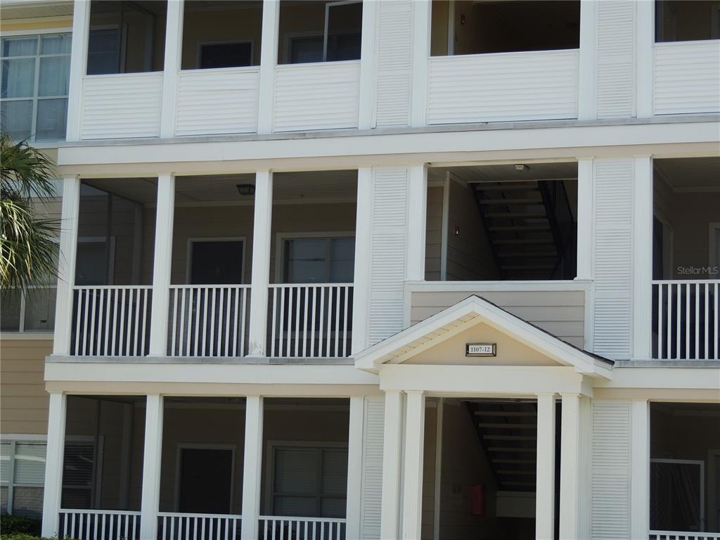 The exterior of a multi-story apartment building features screened-in balconies and a central staircase — 4802 51ST STREET W UNIT 1109, BRADENTON, FL
