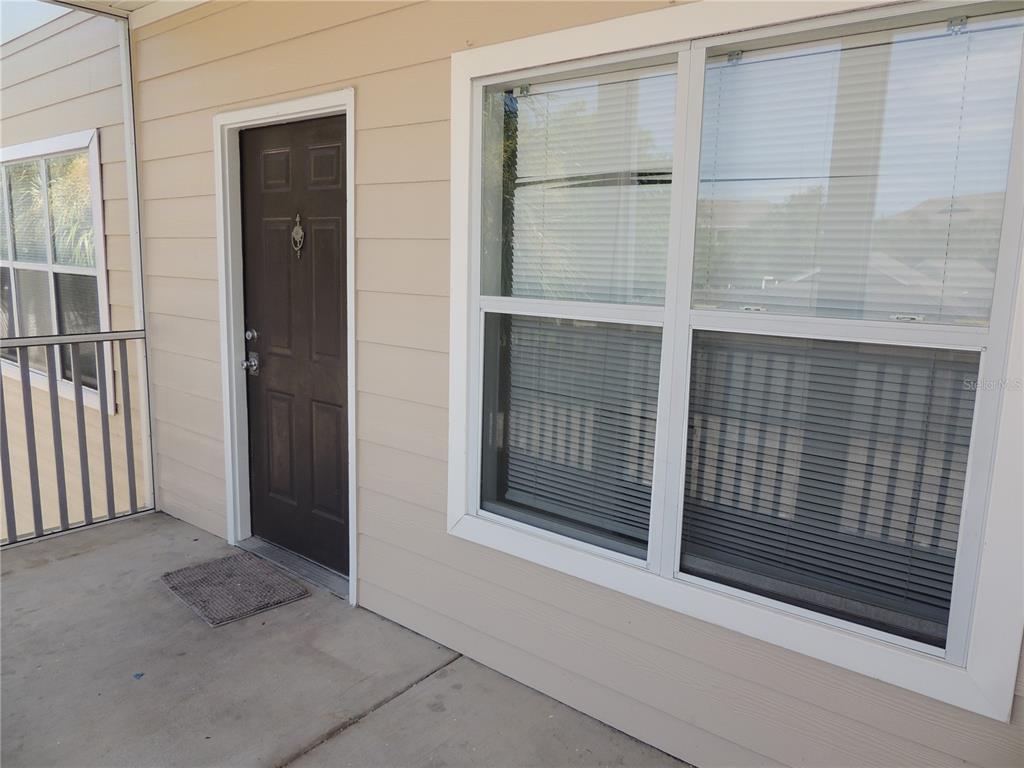 A dark brown front door sits next to a large window on a concrete porch — 4802 51ST STREET W UNIT 1109, BRADENTON, FL