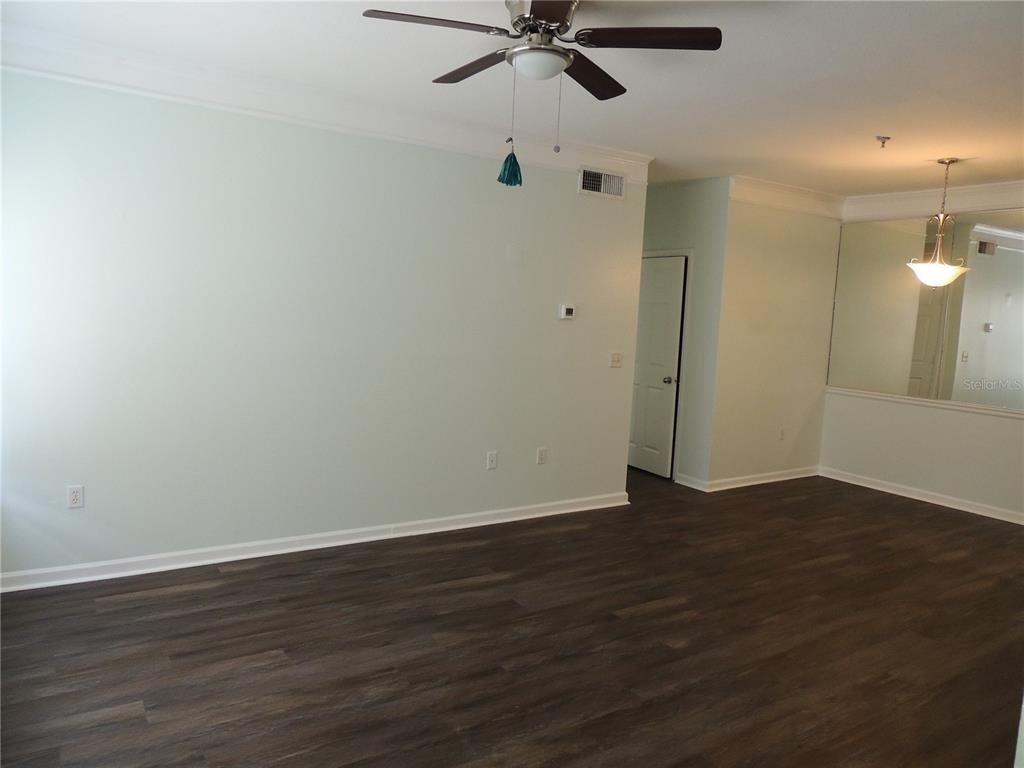 An empty room features light-colored walls, dark wood-look flooring, a ceiling fan, and mirrored walls — 4802 51ST STREET W UNIT 1109, BRADENTON, FL