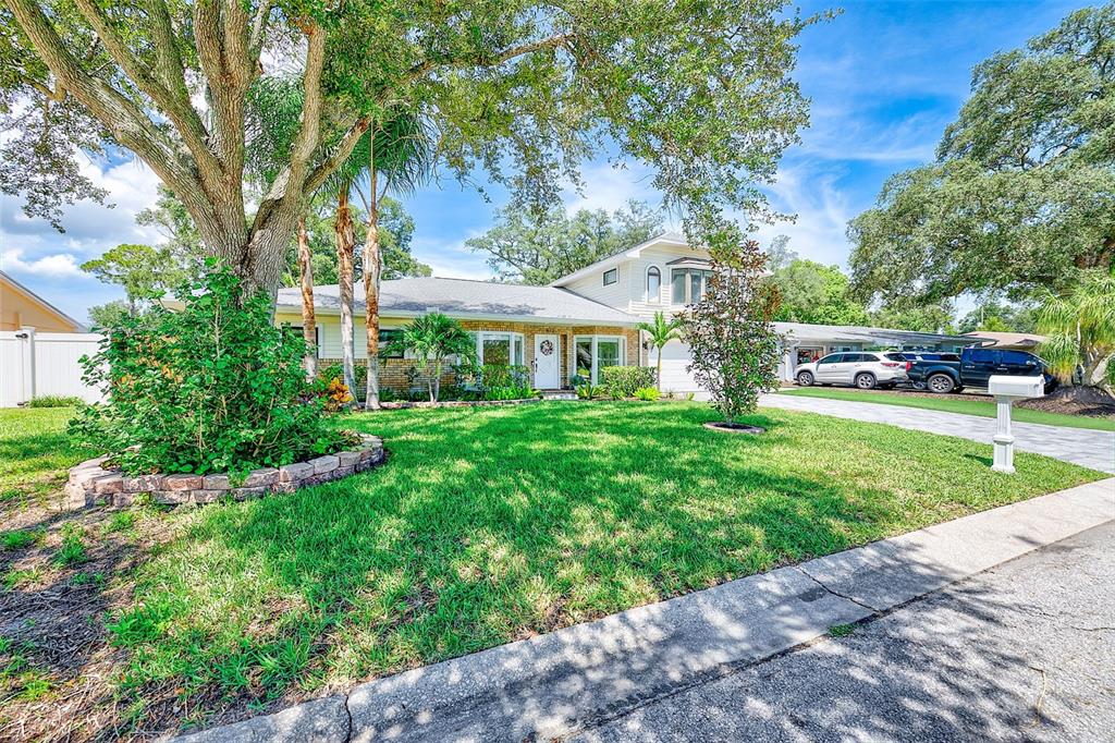A single-story house with a brick facade, a large front lawn, and mature trees — 812 WILLOWBRANCH AVENUE, CLEARWATER, FL