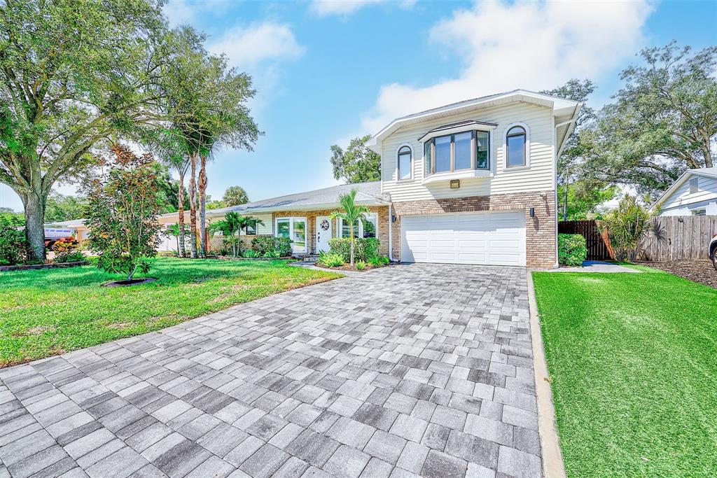 A two-story house with a paved driveway, a white garage door, and a bay window — 812 WILLOWBRANCH AVENUE, CLEARWATER, FL