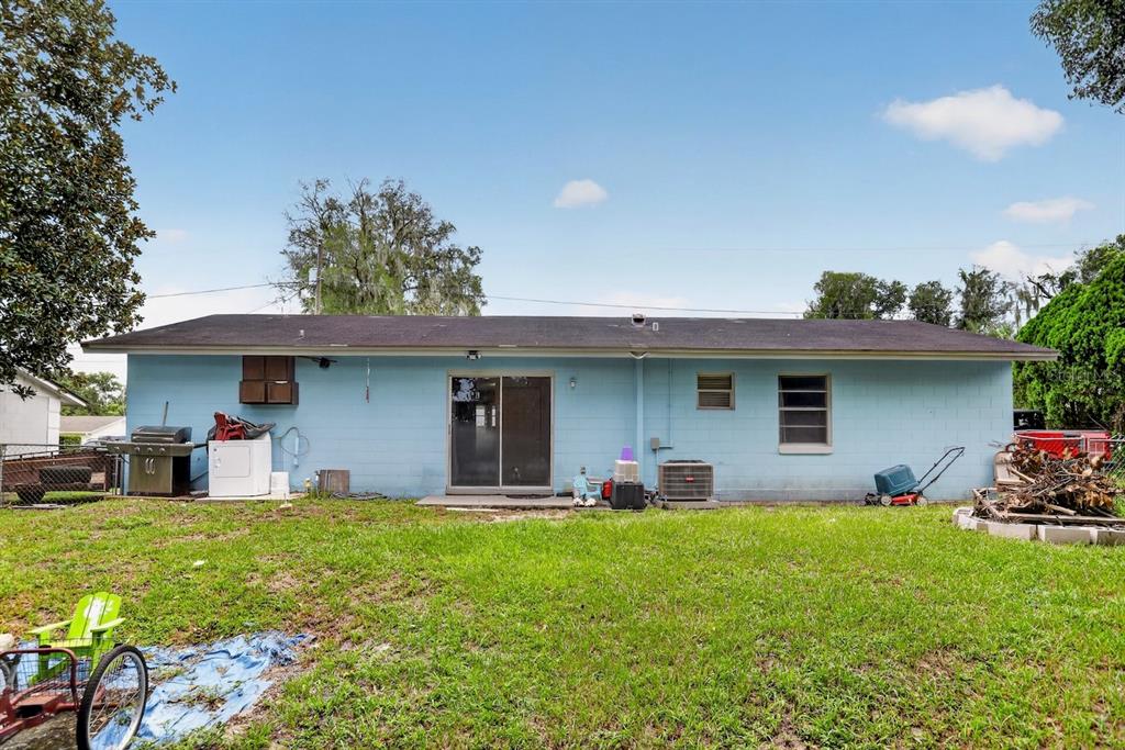 The exterior of a light blue, single-story house with a backyard and sliding glass doors — 359 W LANSDOWNE AVENUE, ORANGE CITY, FL
