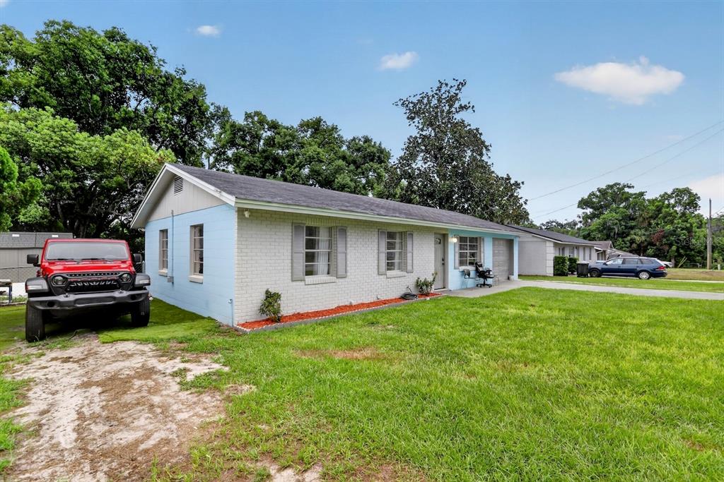 A single-story light blue and white brick house with a red Jeep parked in front — 359 W LANSDOWNE AVENUE, ORANGE CITY, FL