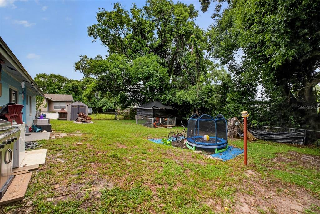 A grassy backyard features a small trampoline, a shed, and a covered outdoor structure — 359 W LANSDOWNE AVENUE, ORANGE CITY, FL