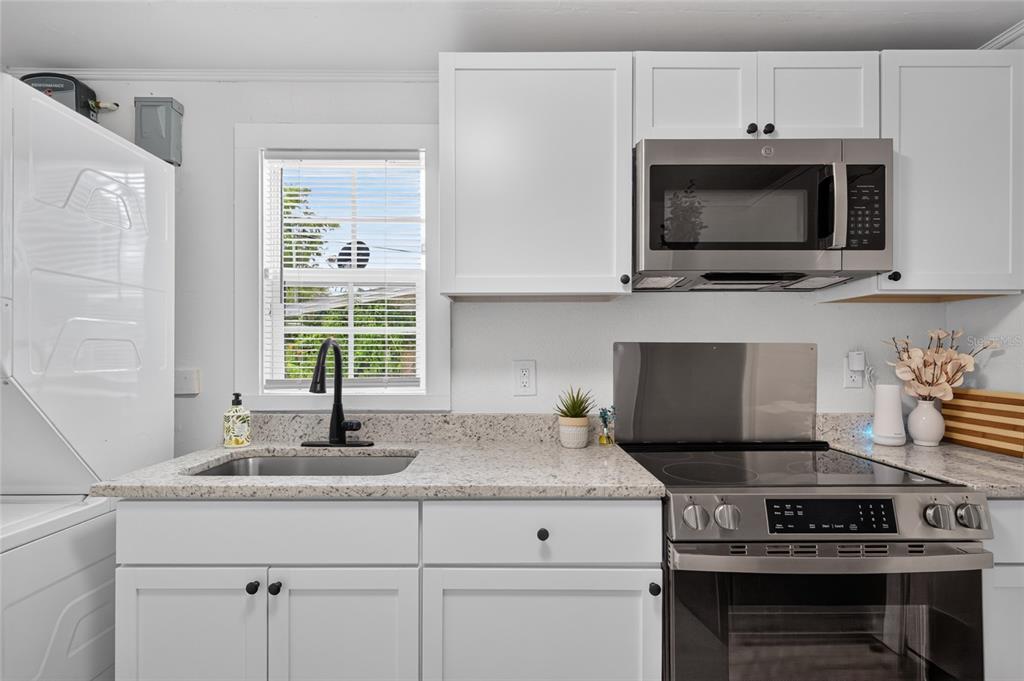 A kitchen features white cabinets, granite countertops, a stainless steel sink, and a microwave oven — 1545 29TH STREET, SARASOTA, FL