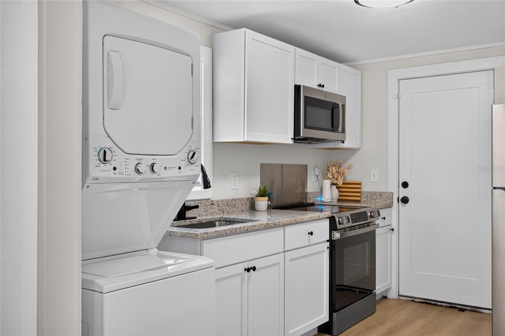 A kitchen features white cabinets, granite countertops, a stainless steel oven, and a stacked laundry unit — 1545 29TH STREET, SARASOTA, FL