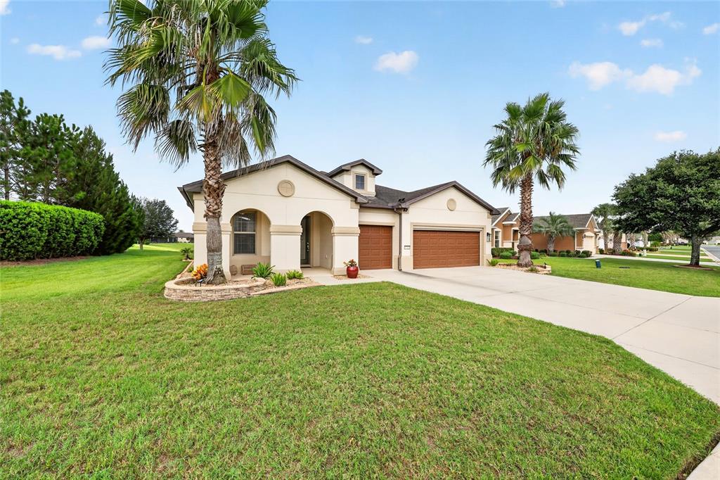 A single-story house with a beige stucco exterior, two garage doors, and two palm trees — 9712 SW 75TH STREET RD, OCALA, FL