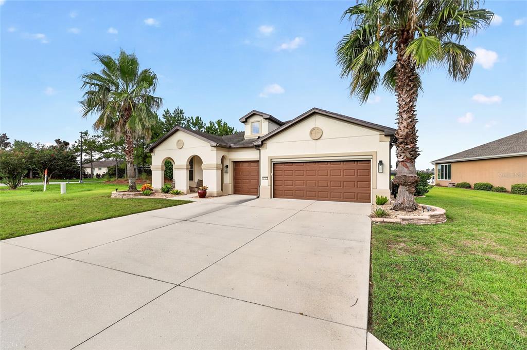 A single-story house with a beige stucco exterior, brown garage doors, and two palm trees — 9712 SW 75TH STREET RD, OCALA, FL