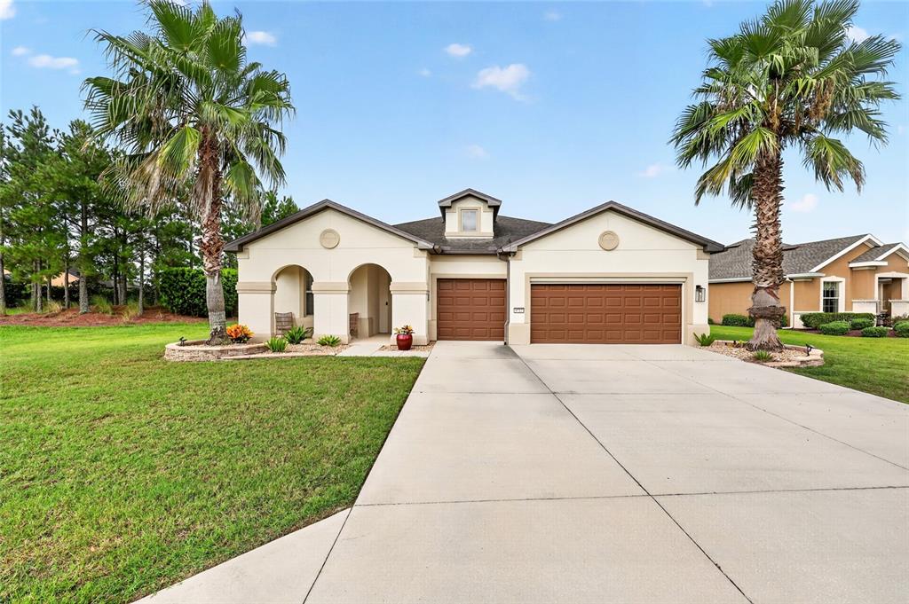 A single-story house with a two-car garage, arched entryway, and two palm trees in front — 9712 SW 75TH STREET RD, OCALA, FL