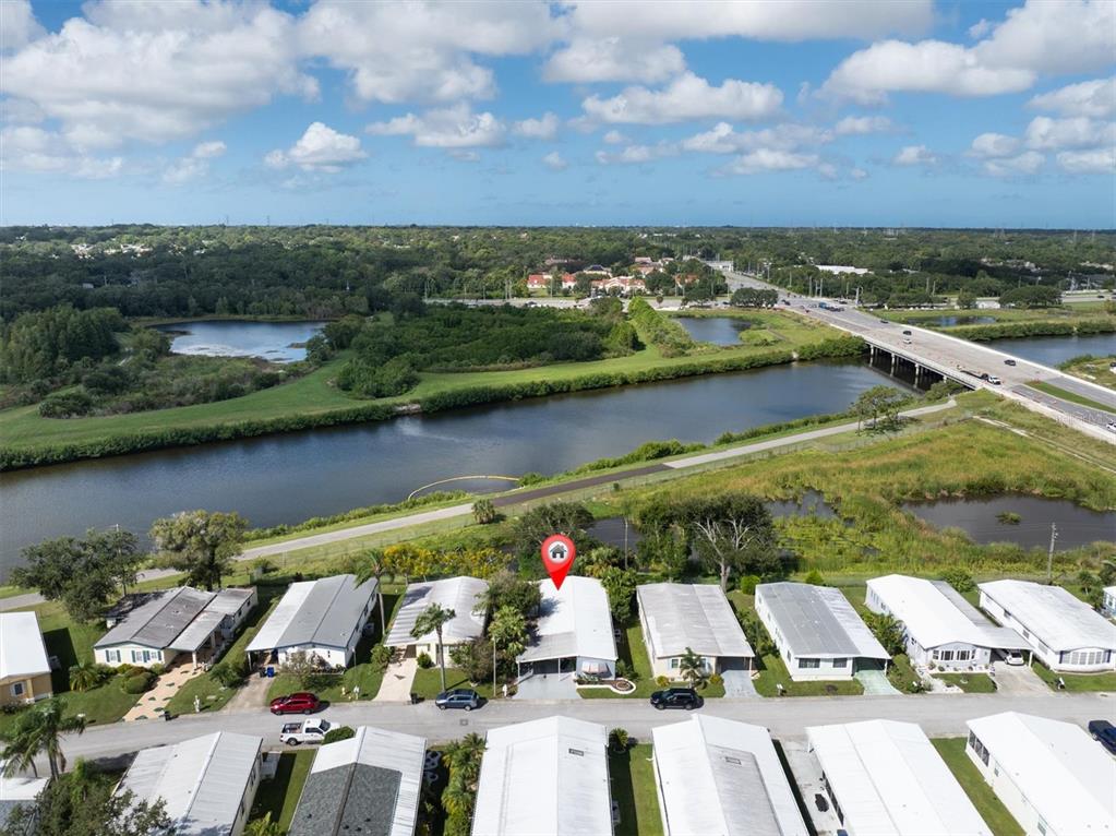 An aerial view shows a row of mobile homes near a canal and a highway bridge — 347 CANAL WAY, OLDSMAR, FL