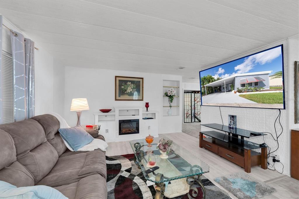 A living room features a grey sofa, a glass coffee table, and a wall-mounted television — 347 CANAL WAY, OLDSMAR, FL