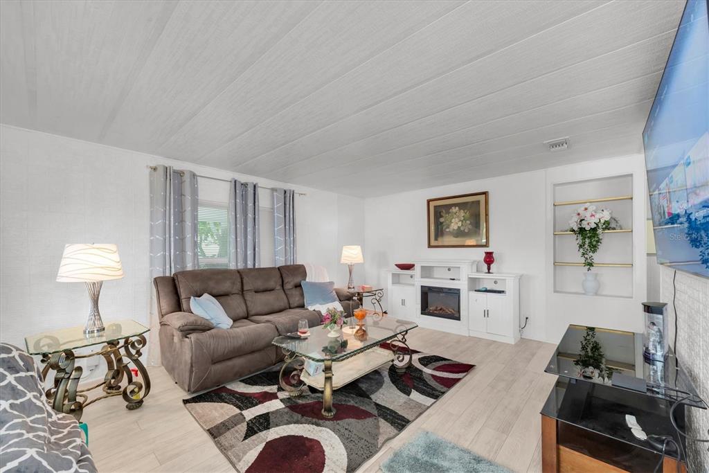 A living room features a brown sofa, a glass coffee table, and a white fireplace — 347 CANAL WAY, OLDSMAR, FL