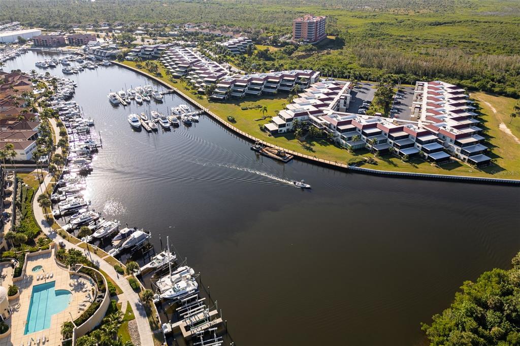 An aerial view shows a marina with docked boats, waterfront condominiums, and a swimming pool — 3250 SOUTHSHORE DRIVE UNIT 55A, PUNTA GORDA, FL