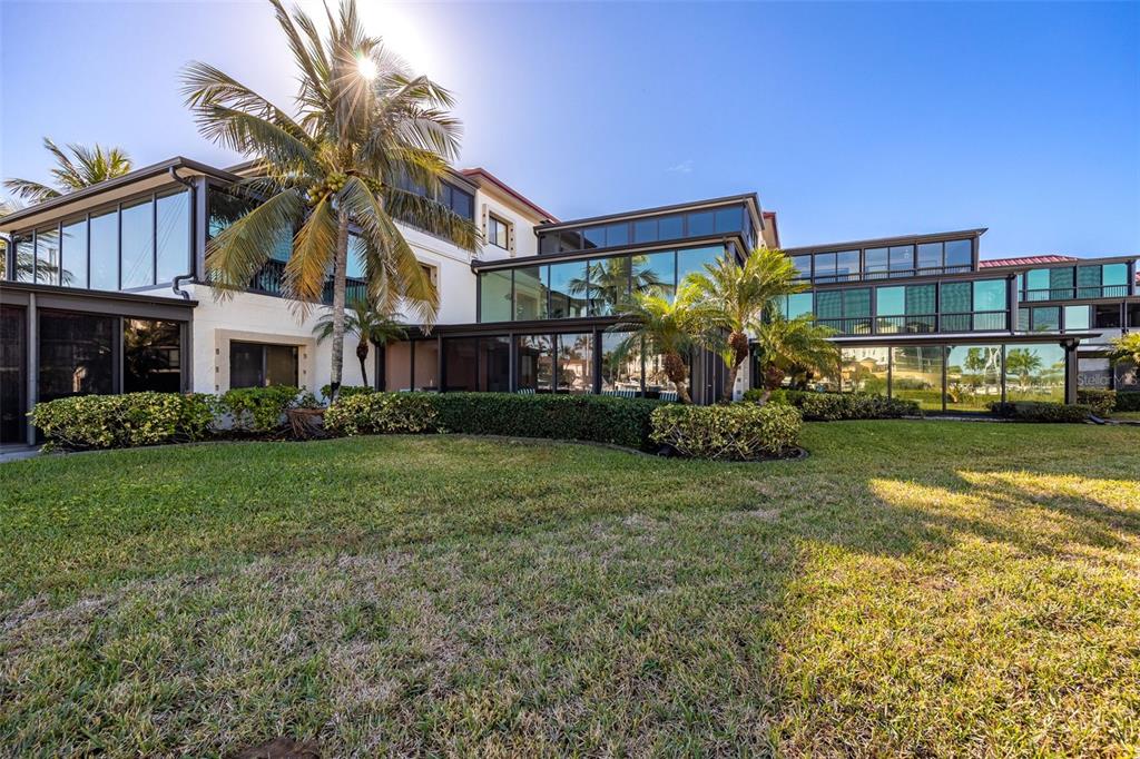 A multi-story building with large glass windows and a palm tree on a grassy lawn — 3250 SOUTHSHORE DRIVE UNIT 55A, PUNTA GORDA, FL