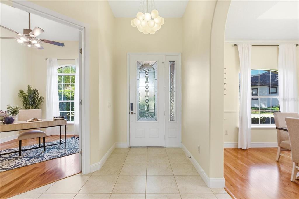 A bright foyer with tile flooring features a white front door and arched entryways — 1064 CEASARS COURT, MOUNT DORA, FL