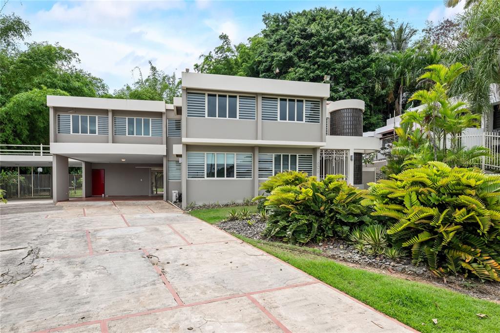 A two-story house with a concrete driveway, large windows, and lush landscaping in the front — 2 CALLE 2 TINTILLO HILLS UNIT 606, GUAYNABO, PR