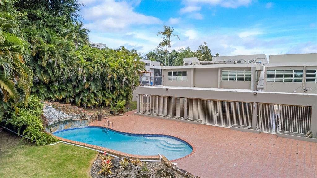 An outdoor swimming pool sits on a tiled patio next to a multi-story building — 2 CALLE 2 TINTILLO HILLS UNIT 606, GUAYNABO, PR