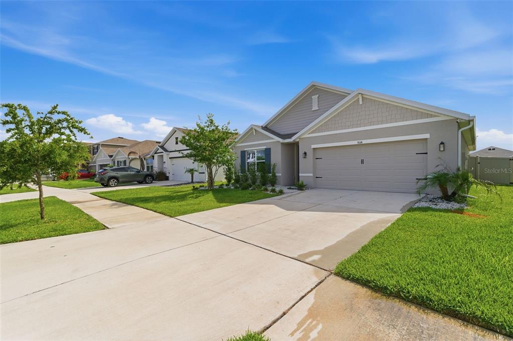 A single-story suburban house with a gray exterior, two-car garage, and a concrete driveway — 9014 FORGE BREEZE LOOP, WESLEY CHAPEL, FL